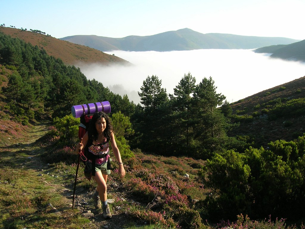 Peregrina caminando hacia Santiago entre montañas
